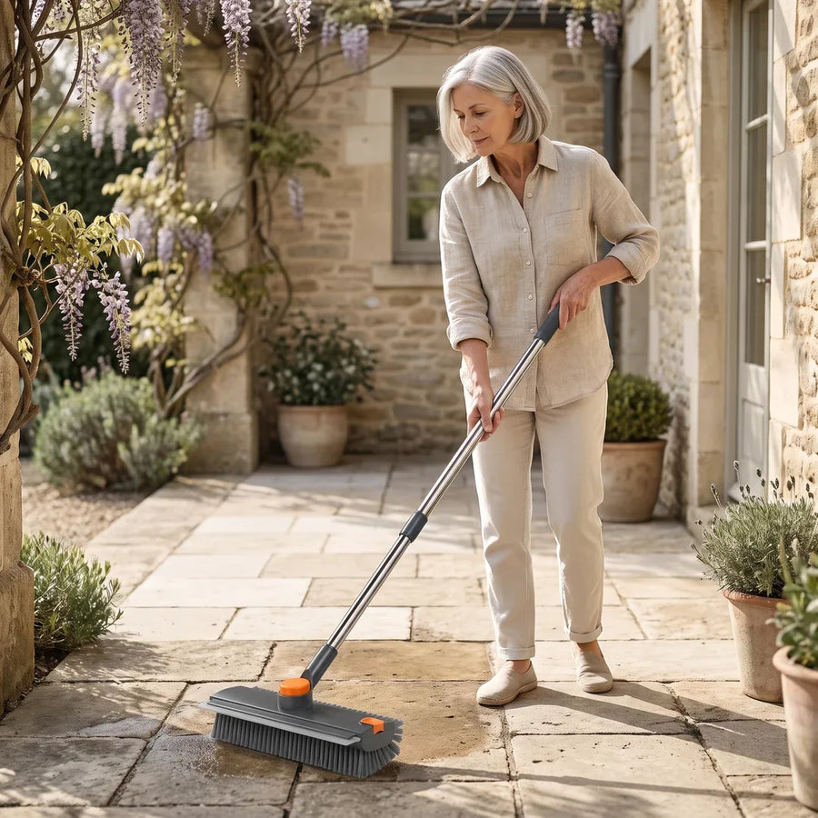 Nettoyer une terrasse en dalles, debout, avec une brosse à manche long.